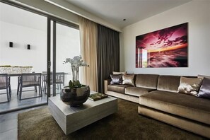 Relax in this stylish living room with a large window offering a view of the outdoors, a comfortable sofa, and a beautiful abstract painting.