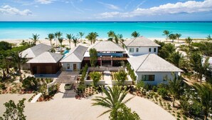 A beachfront property with multiple houses, a covered patio, and a view of the ocean. - Hawksbill Estate – A Grand Beachfront Estate on Grace Bay, Turks & Caicos (Leeward Settlement)