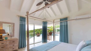 A bedroom with a four-poster bed, a wooden dresser, and a large window with curtains. - Villa Sea Vous Play – Relaxed Oceanview Living in St. Martin (Cul-de-Sac)