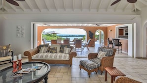A spacious living area with wicker furniture, a glass coffee table, and ceiling fans. - Villa Sea Vous Play – Relaxed Oceanview Living in St. Martin (Cul-de-Sac)