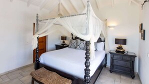 A four-poster bed with a canopy, two bedside tables with lamps, a bench, and a wooden door. - Villa Sea Vous Play – Relaxed Oceanview Living in St. Martin (Cul-de-Sac)