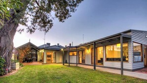 A modern house with a covered patio, a lawn, and a large tree. - 5 Connelly - Echuca Holiday Homes (Echuca)