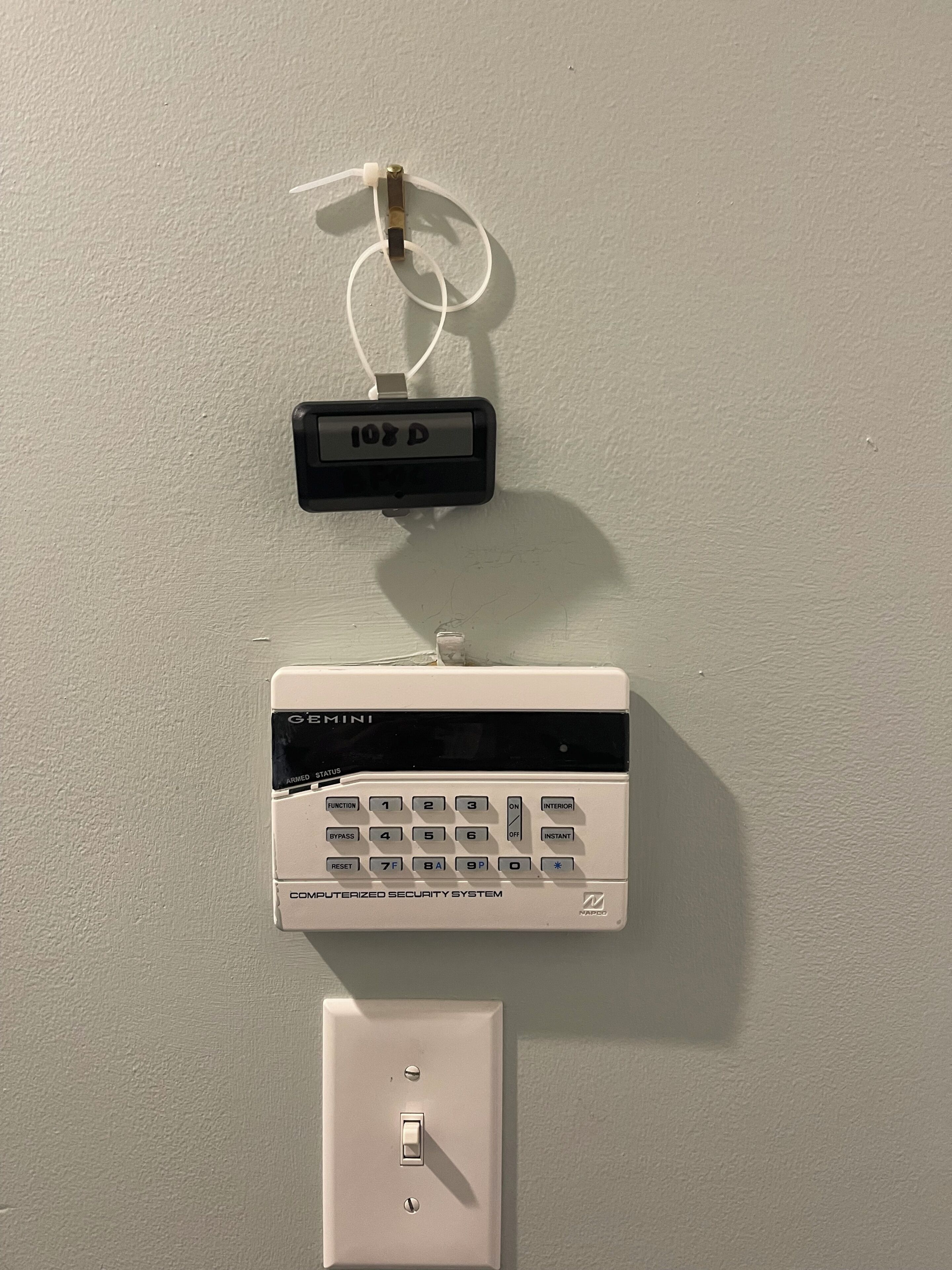 A wall-mounted security system with a keypad and a digital display.