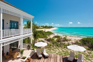 Ein Strandgrundstück mit einer Holzterrasse, Liegestühlen und Sonnenschirmen.
