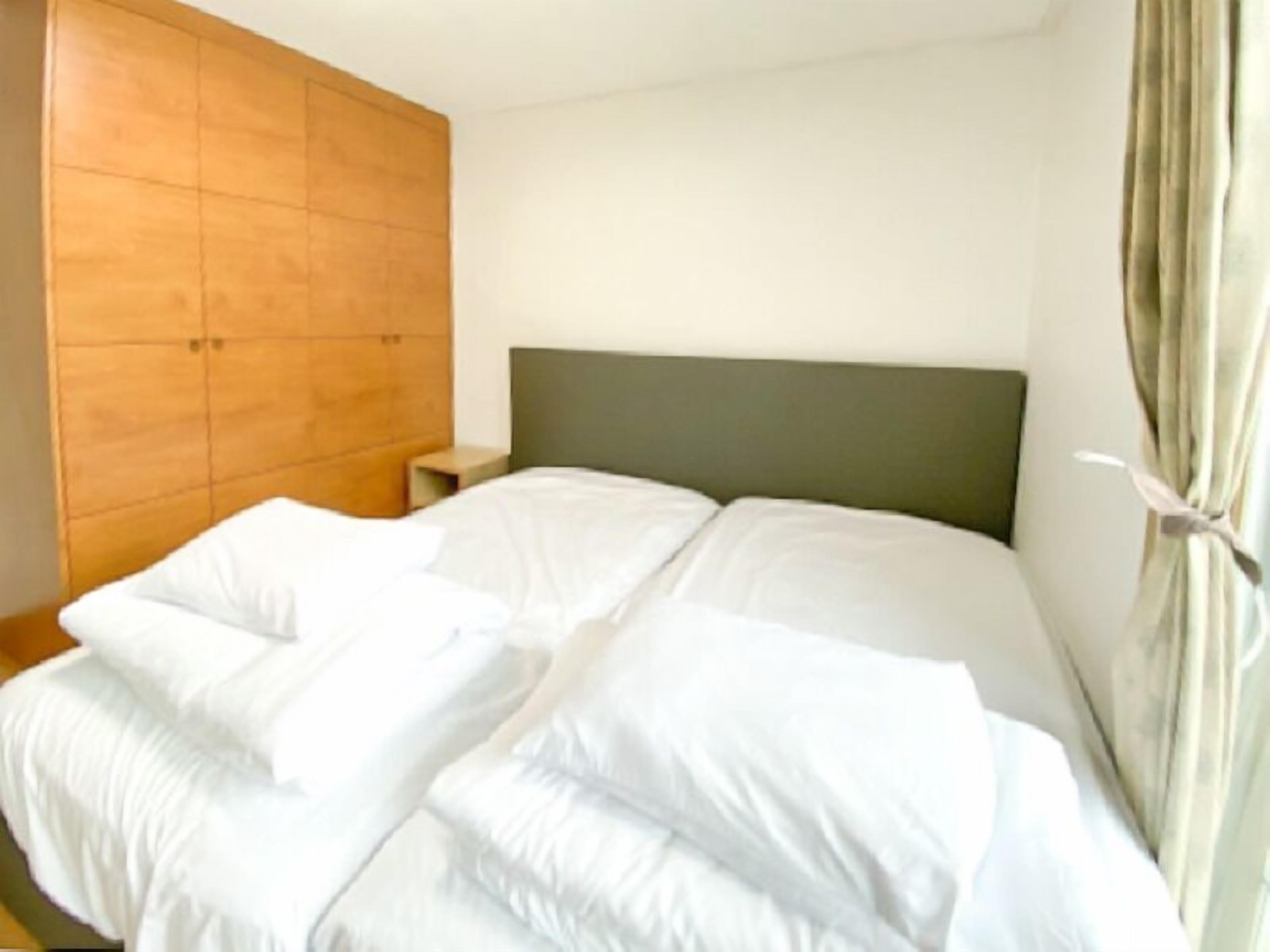 Een slaapkamer met een bed, een houten garderobe en een nachtkastje.