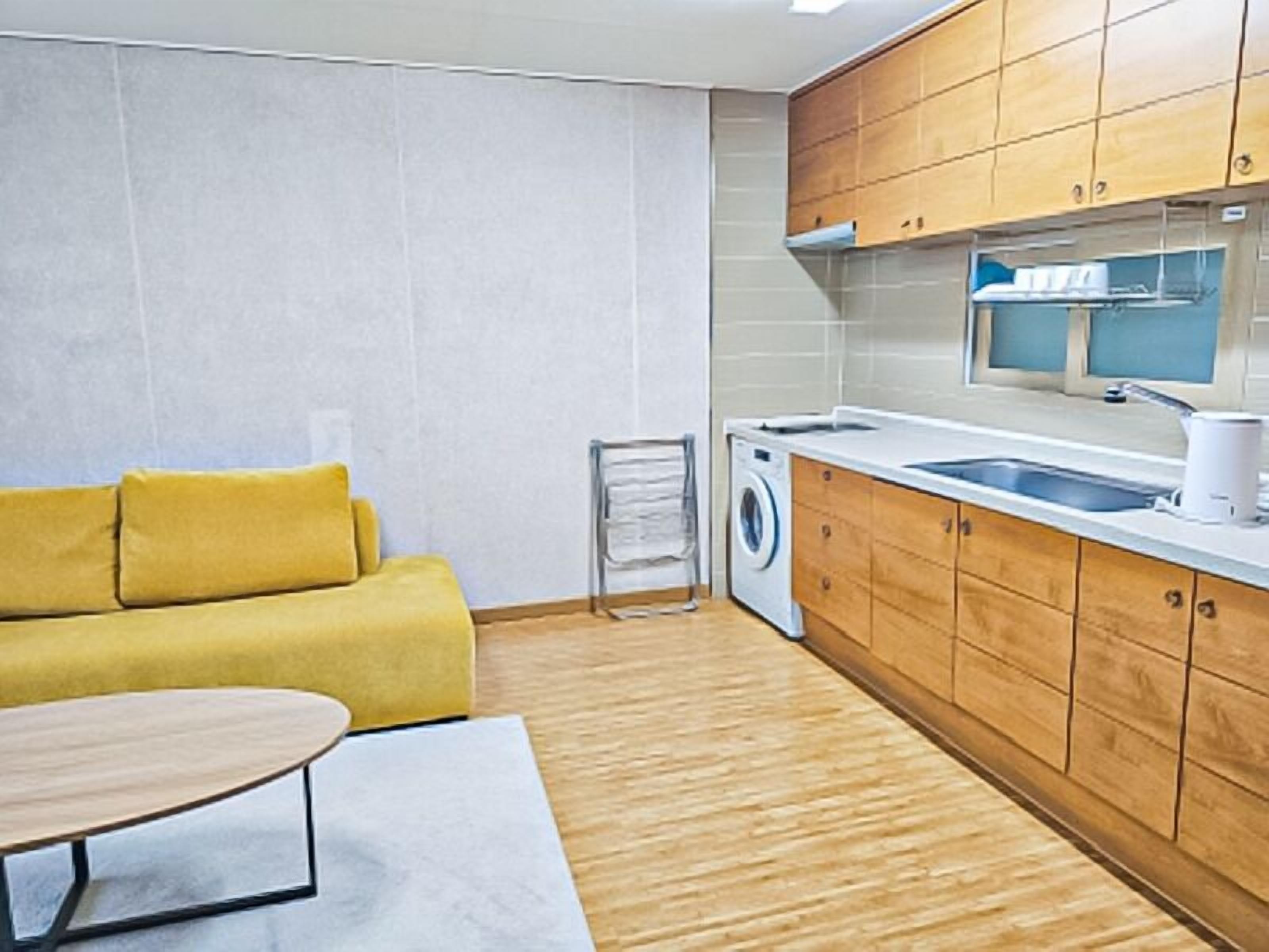 A compact kitchen with wooden cabinets, a built-in washing machine, and a sink.