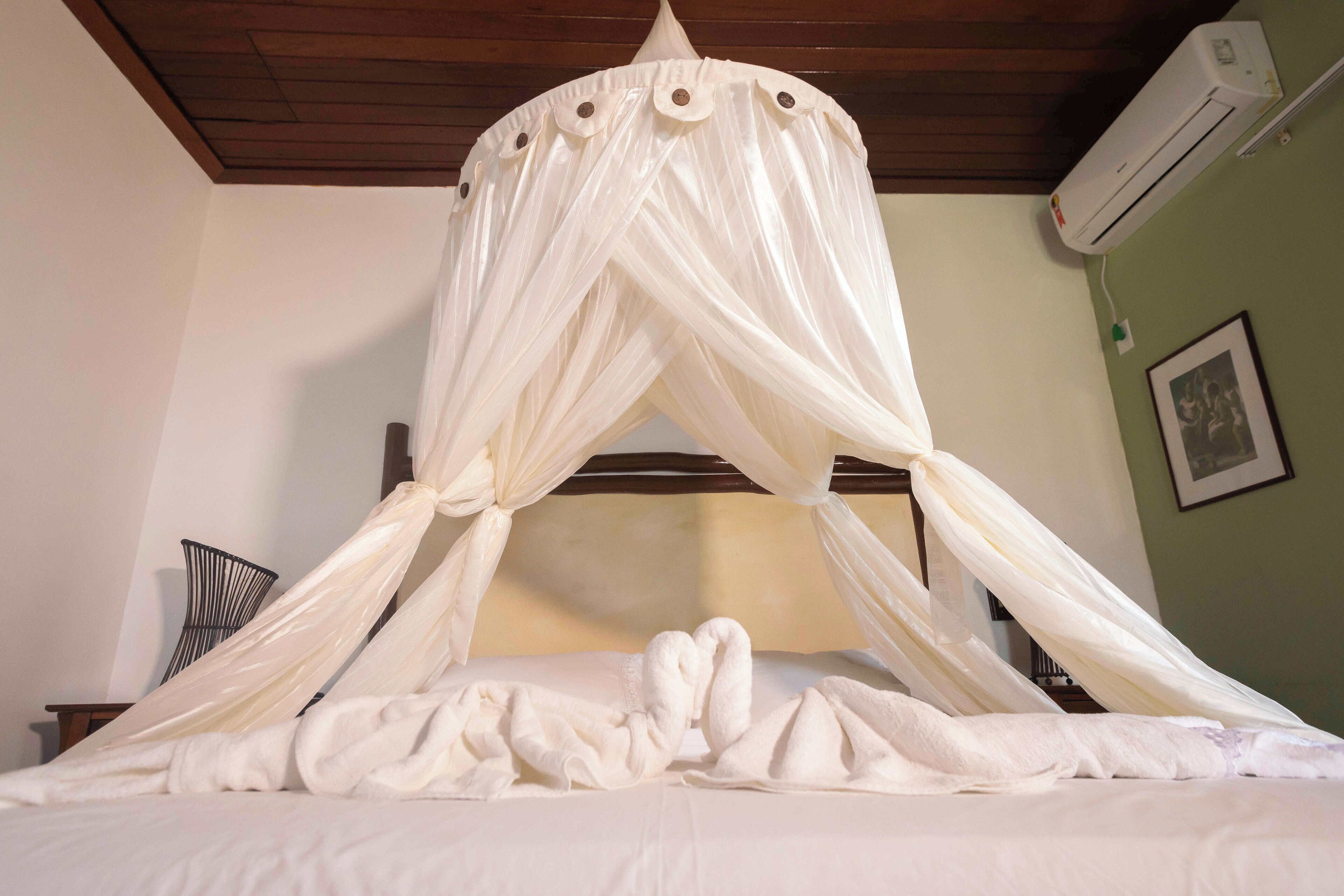 Una cama con dosel, un aire acondicionado de pared y un cuadro enmarcado.