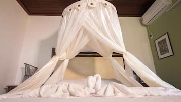 Una cama con dosel, un aire acondicionado de pared y un cuadro enmarcado.