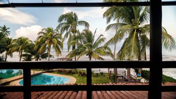 Zona de piscina con vista a la playa y palmeras.