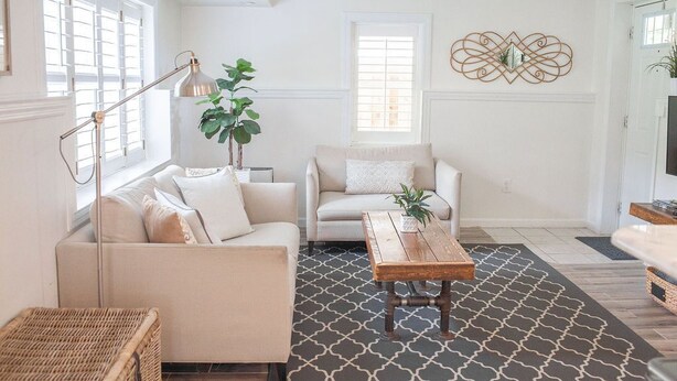 A living room with a sofa, a coffee table, and a floor lamp. There is a plant and a decorative wall piece. - The Sycamore Bungalow located near attractions in The Amish Country.  (Lancaster)