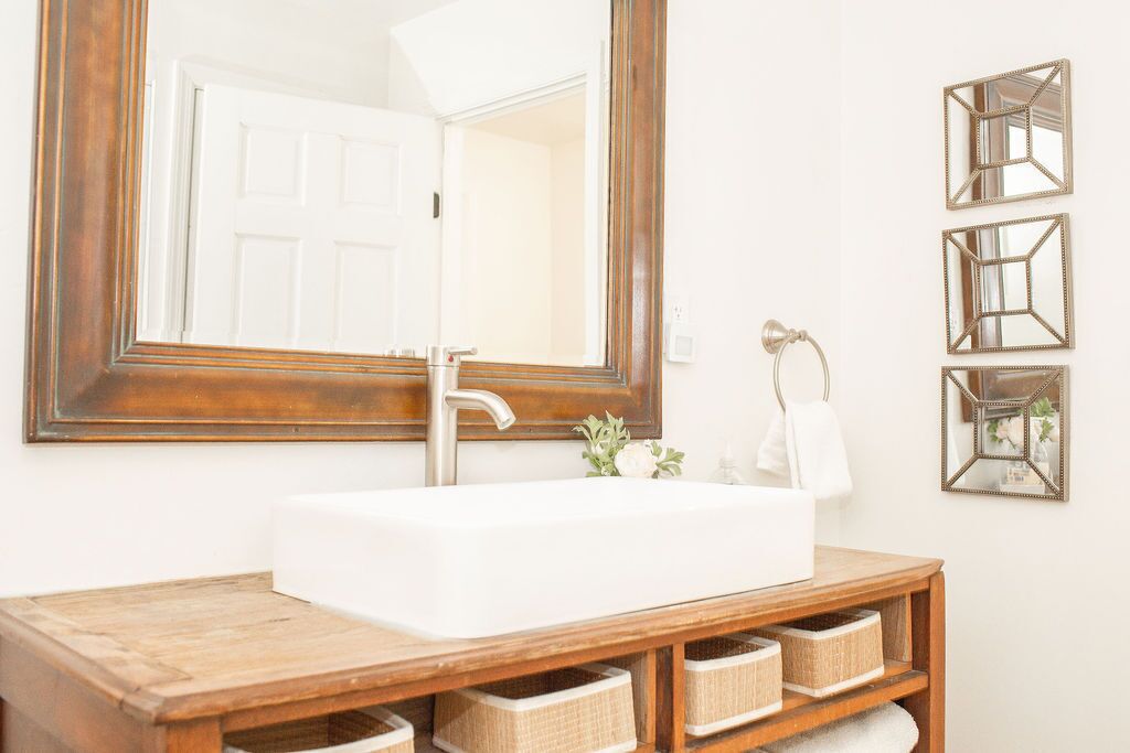 A bathroom with a large mirror, a white sink, and wooden storage shelves.