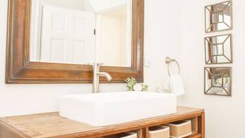 A bathroom with a large mirror, a white sink, and wooden storage shelves.