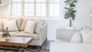 A modern living room with a beige sofa, a wooden coffee table, and a patterned rug. - The Sycamore Bungalow located near attractions in The Amish Country.  (Lancaster)
