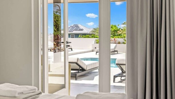 Et moderne hotelværelse med udsigt til en pool og et hus i baggrunden.