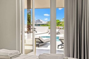 Quarto de hotel moderno com vista para uma piscina e uma casa ao fundo.