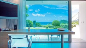 A modern room with a large window offering a view of the ocean and greenery. - Villa NIRVANA – A Temple of Contemporary Luxury & Tranquil Bliss in St. Barth (Gustavia)