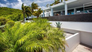 A modern building with a flat roof, surrounded by lush greenery and palm trees. - Villa NIRVANA – A Temple of Contemporary Luxury & Tranquil Bliss in St. Barth (Gustavia)