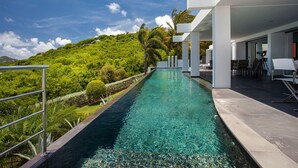 A modern pool area with clear water, surrounded by lush greenery and white architecture. - Villa NIRVANA – A Temple of Contemporary Luxury & Tranquil Bliss in St. Barth (Gustavia)
