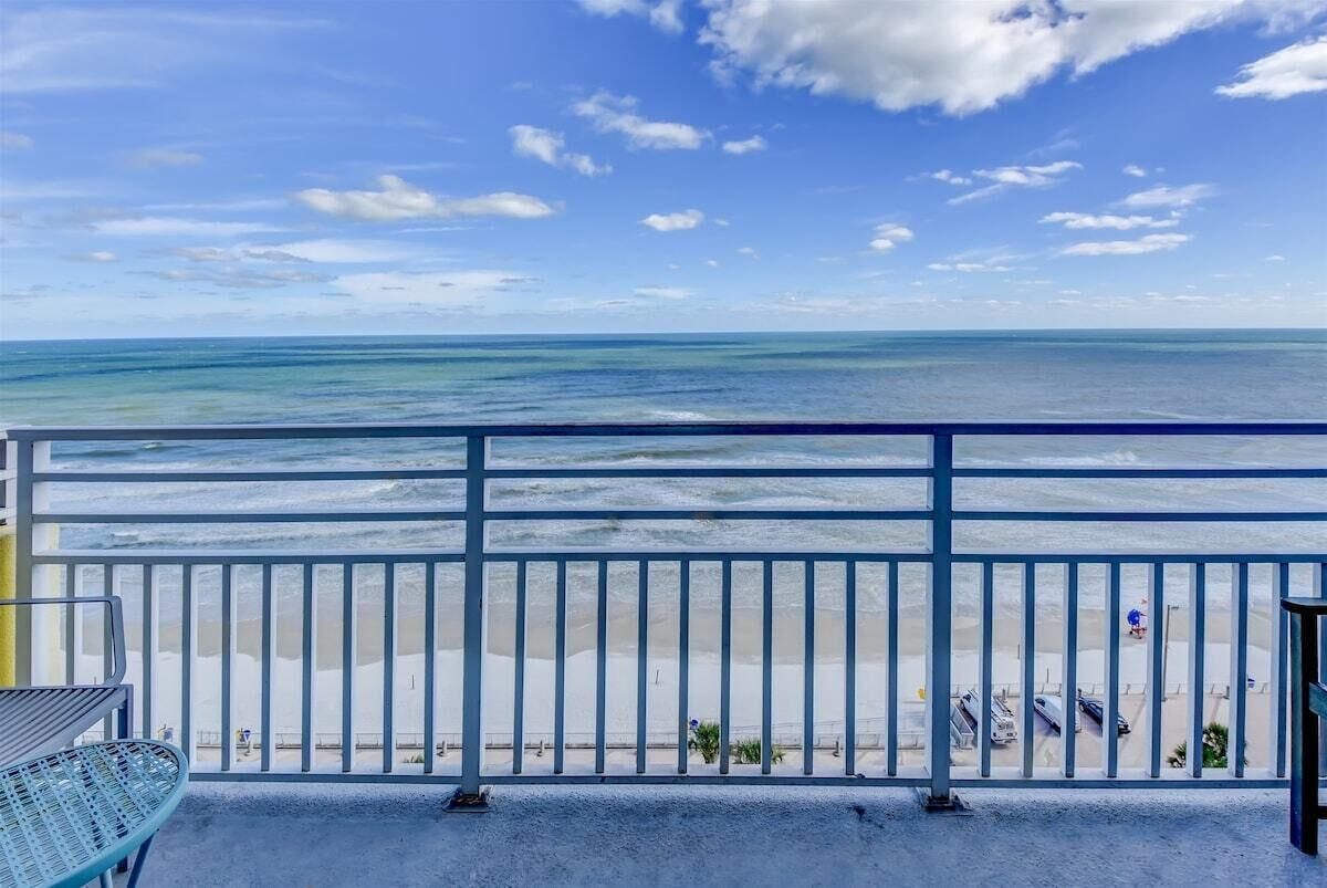 A balcony with a view of the beach and ocean.