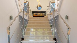 Una escalera moderna con barandillas de vidrio y una vista de un cuadro en la parte superior.