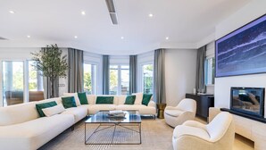 Una sala de estar moderna con un sofá modular, una mesa de centro de vidrio y una chimenea.