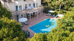 Una casa grande con piscina, mobiliario exterior y balcón.
