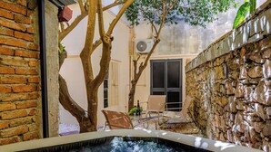 A hot tub with a stone wall and a tree in the background. - EIDOS - holiday house Taormina center (Taormina)