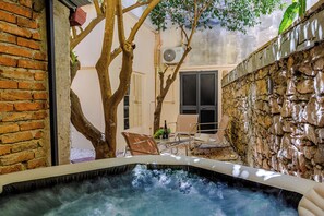 A hot tub with a stone wall and a tree in the background. - EIDOS - holiday house Taormina center (Taormina)