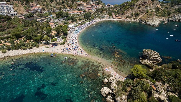 A coastal area with a beach, clear waters, rocky outcrops, and buildings in the background. - EIDOS - holiday house Taormina center (Taormina)