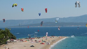 A beach with multiple kites flying, a sandy shore, and a calm sea. - Modern & cozy apartment in amazing location just opposite to Dioclation's Palace (Split)