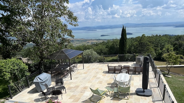 Eine Terrasse im Freien mit Steinboden, überdachter Sitzgelegenheit und Pflanzkübeln.