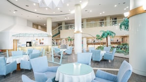 A spacious lobby with a central seating area, a staircase, and a reception desk.