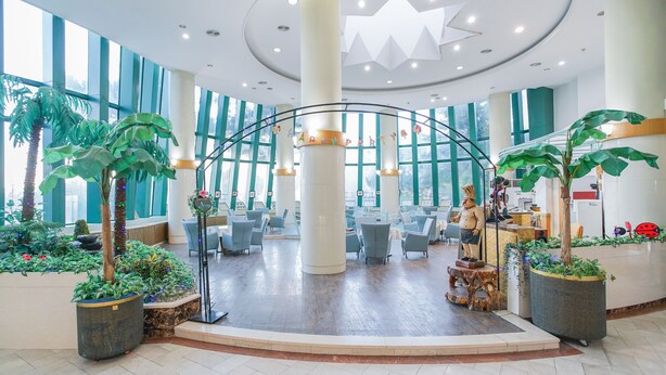A spacious lobby with a central seating area, large windows, and decorative plants.