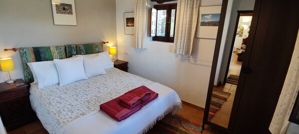 A neatly made bed with a floral bedspread, two bedside lamps, and a red towel on the bed. - Rural accommodation with sumptuous garden and magnificent panoramic view (Pórtugos)