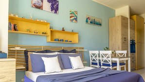 Un dormitorio con cama, cabecera de madera, estantes con adornos, un escritorio con silla y un armario.
