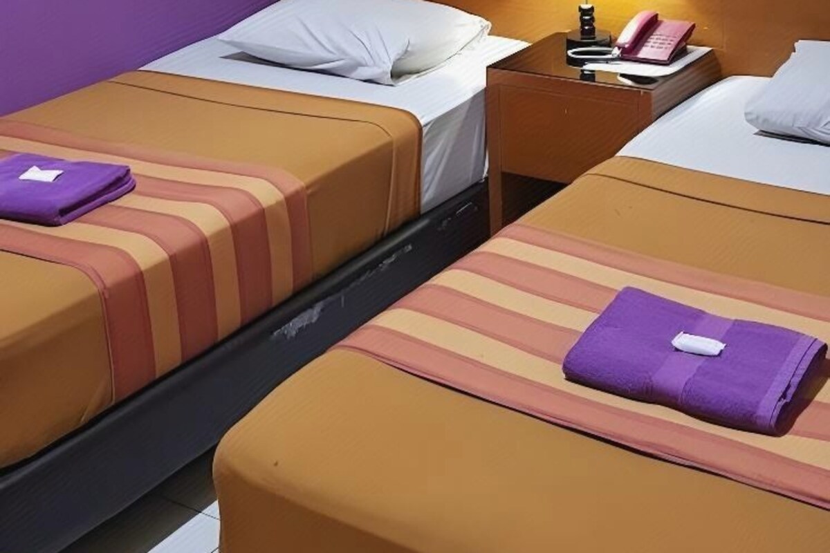 Una habitación de hotel con dos camas, una mesita de noche con una lámpara y un teléfono.
