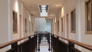 A long, narrow corridor with a central red carpet, wooden railings, and a skylight at the end. - Hotel DeQur Jakarta Kota (Jakarta)