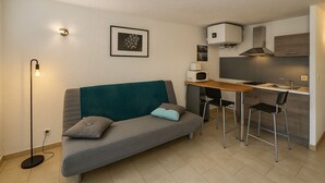 Un espace de vie compact comprenant un canapé, une petite table à manger et un coin cuisine.