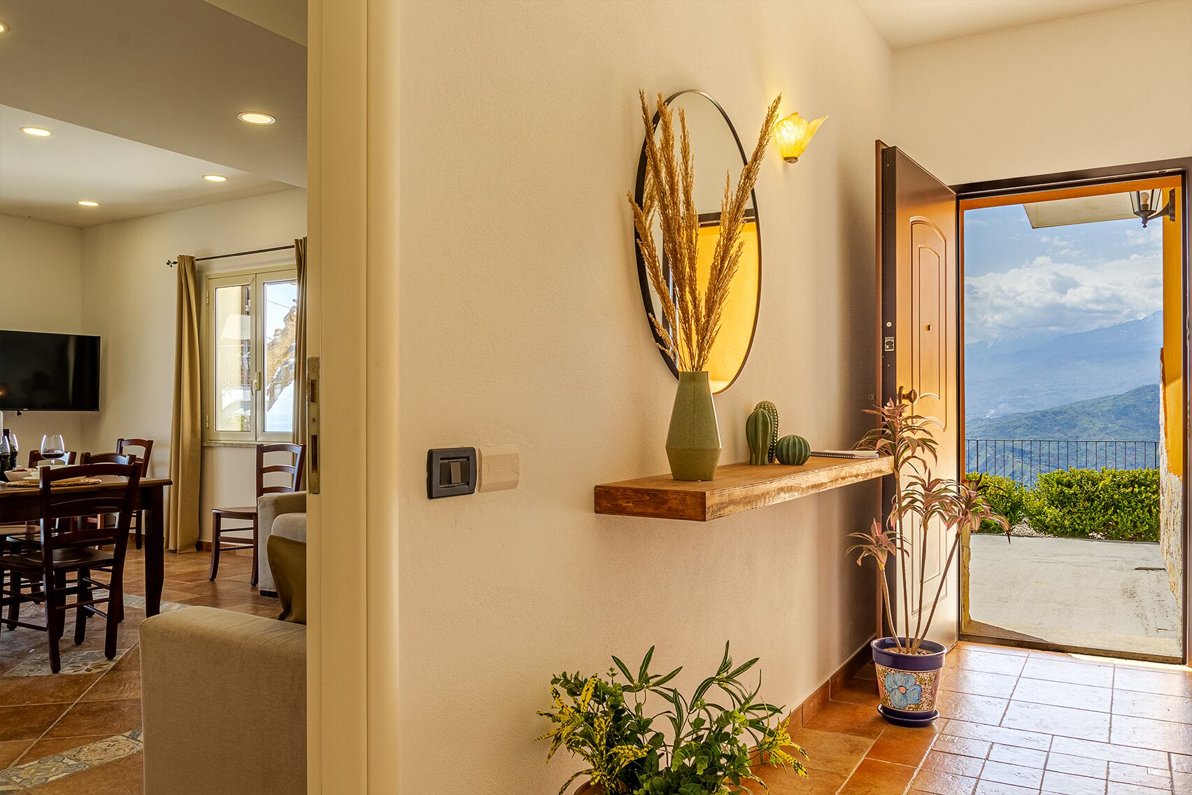 Ein modernes Interieur mit Essbereich, einem Wandspiegel und Blick ins Freie.
