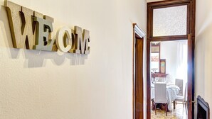 Un espace d’accueil avec une pancarte indiquant « BIENVENUE » et une salle à manger visible à travers une porte ouverte.