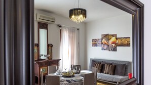 Un coin repas avec une table ronde dressée pour quatre personnes, un canapé, un lustre et des œuvres d’art accrochées au mur.