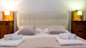 A neatly made bed with two pillows, a quilt, and two rolled towels. There are two bedside tables with lamps. - TYSANDROS - SEA VIEW (Giardini-Naxos)