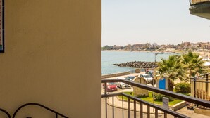 A balcony with a view of a coastal area, including parked cars and a rocky shoreline. - TYSANDROS - SEA VIEW (Giardini-Naxos)