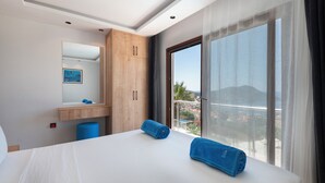 Ein Hotelzimmer mit Bett, einem Holzschrank, einem Badezimmer und einem großen Fenster mit Aussicht.