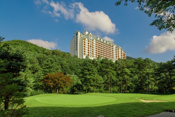 Un hotel de estilo arquitectónico tradicional, rodeado de exuberante vegetación y un campo de golf bien cuidado.