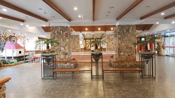 A spacious lobby with stone pillars, benches, and potted plants. - Yangji Pine Resort (Yongin)