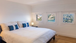 A bedroom with a large bed, white walls, and three windows offering views of a coastal landscape. - Sea Life Taormina - Infinity pool (Taormina)