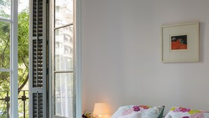 A bedroom with a bed, pillows, a nightstand, a lamp, and a framed picture on the wall. - Cozy Flat with Unbeatable Views of Sagrada Familia (Barcelona)