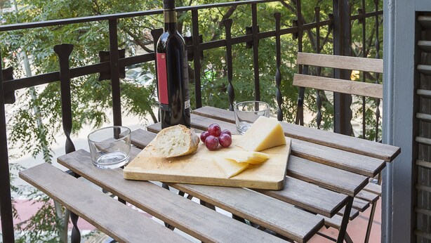 A balcony with a table set for a meal, featuring bread, cheese, and grapes. - Cozy Flat with Unbeatable Views of Sagrada Familia (Barcelona)