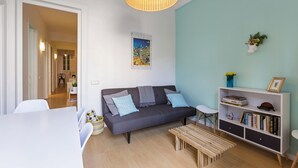 A modern living room with a grey sofa, a white coffee table, a bookshelf, and a wicker lamp. - Cozy Flat with Unbeatable Views of Sagrada Familia (Barcelona)